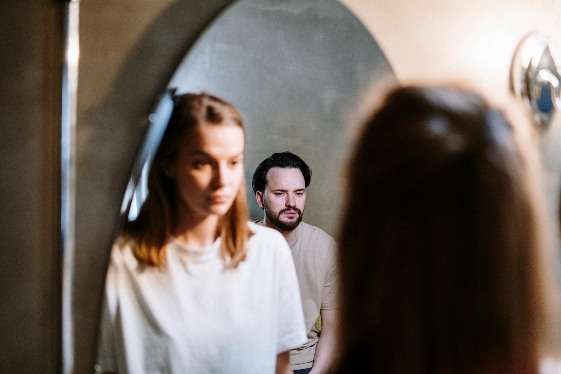 A woman looking at her husband's reflection in the bathroom mirror | Source: Pexels