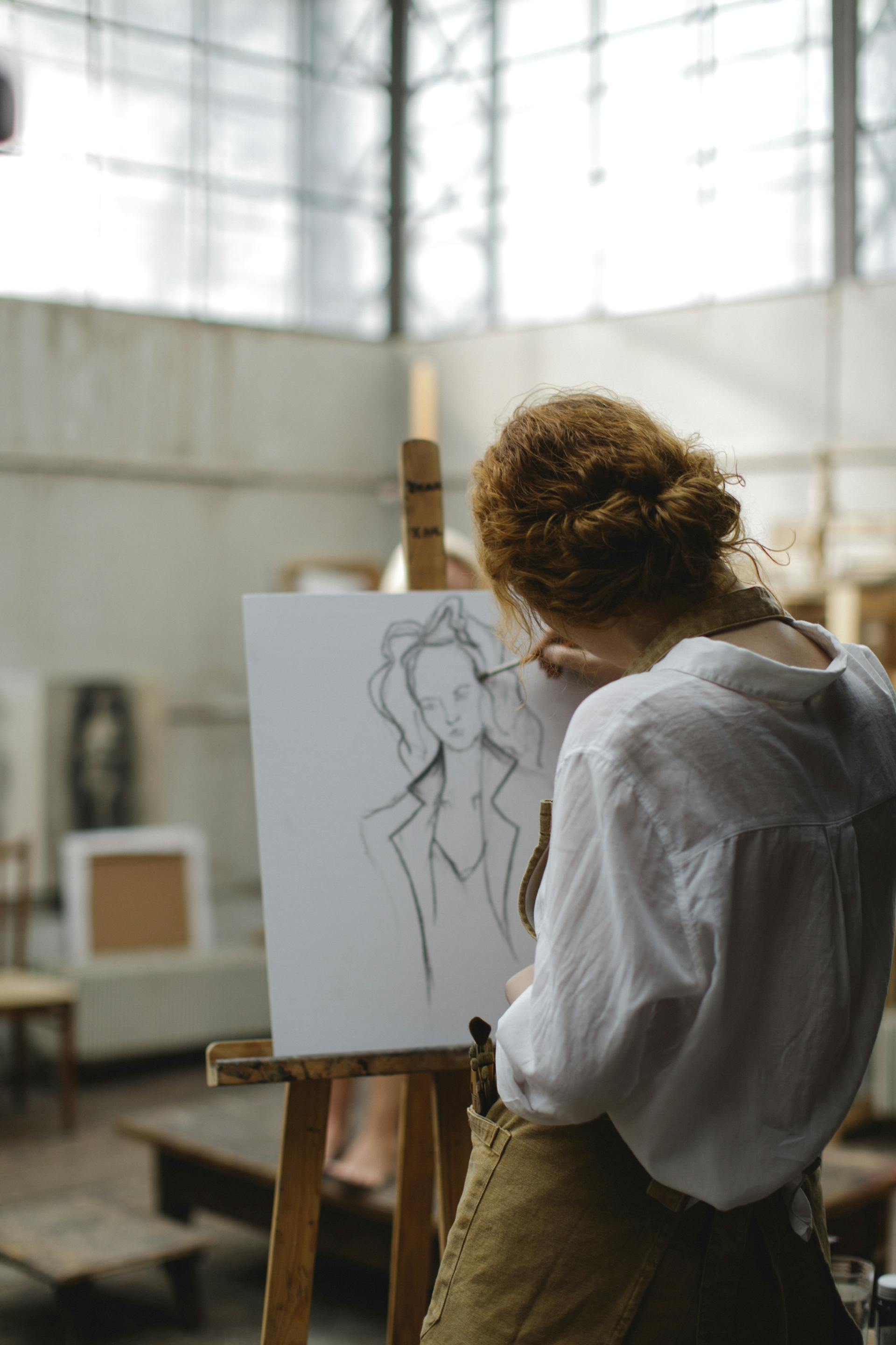 Rear view of a woman sketching a picture on a white board | Source: Pexels