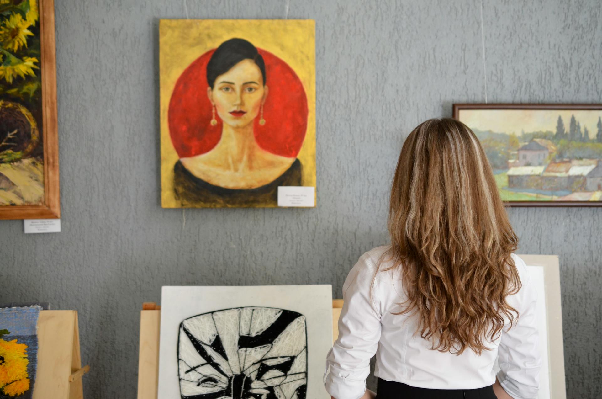 A young woman looking at paintings displayed on the wall | Source: Pexels